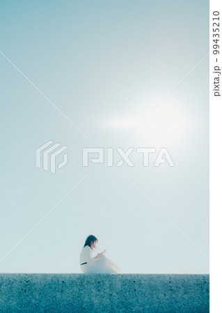 浜辺に佇み本を持っている若い女性の写真 浜辺に佇み本を持っている若い女性の写真 99435210