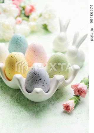 Easter decor. Colored Easter eggs on a ceramic stand and decorative rabbits. 99436574