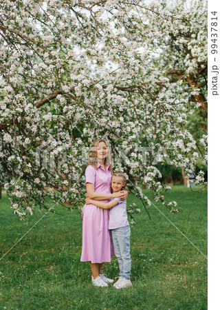 Mom and little daughter are walking through a blooming spring garden 99437814