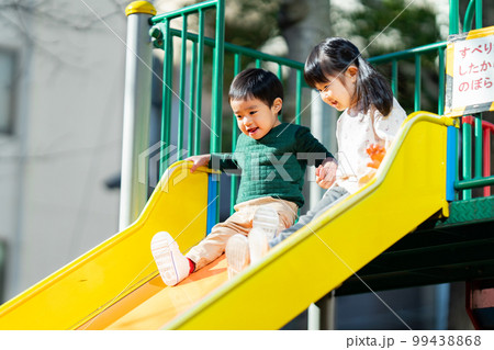 手を繋いで滑り台を滑る子供達 99438868
