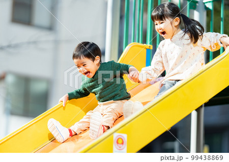手を繋いで滑り台を滑る子供達 99438869