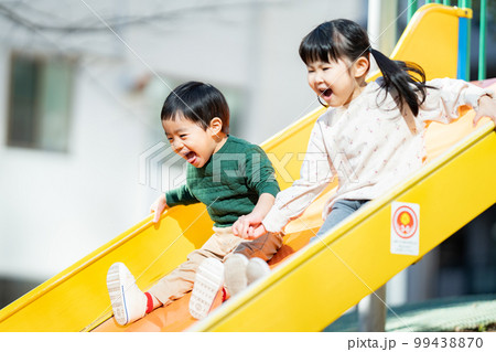 手を繋いで滑り台を滑る子供達 99438870