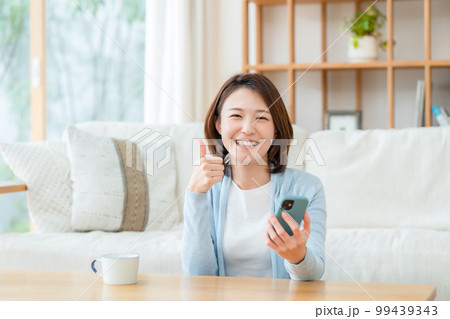 スマホを持つミドル女性　サムズアップ 99439343