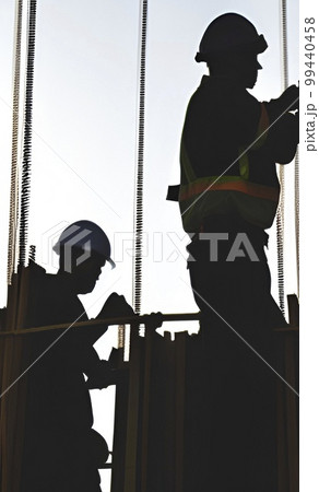 silhouette of worker at the construction site at sunset 99440458