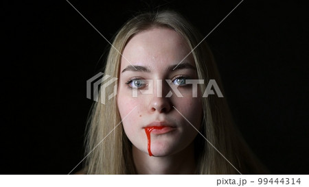 A young woman pours blood from her mouth close-up A young woman pours blood from her mouth close-up 99444314