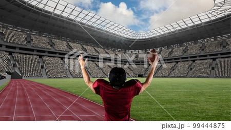 Composition of male american football player holding ball and raising hands over sports stadium 99444875