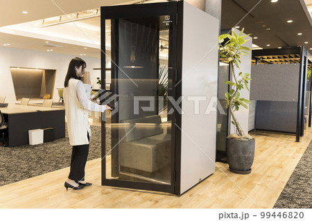 デザインオフィスの個室ブースに入る若い女性 デザインオフィスの個室ブースに入る若い女性 99446820