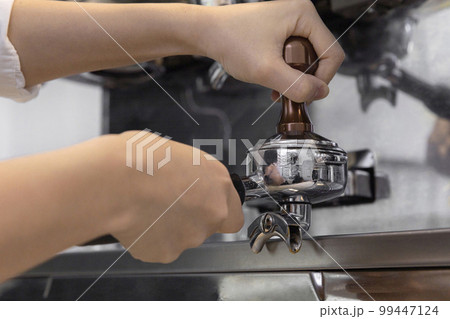 barista tamping coffee in cafe 99447124