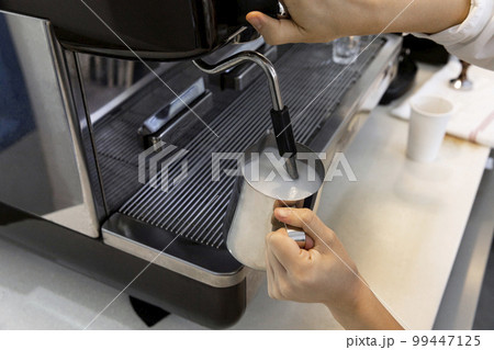 barista steaming milk for cafe latte in cafe 99447125