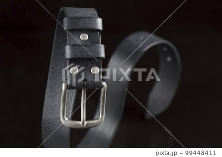 Black leather belt on a dark background. Leather products. Black leather belt on a dark background. Leather products. 99448411