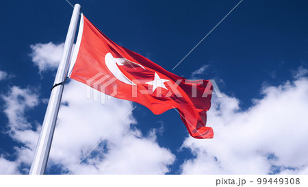 The Turkish flag is being raised. A close-up. A blue sky with clouds in the background. The national flag of Turkey. 99449308