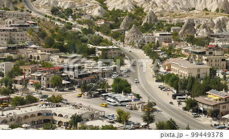 View of old houses, bus station and street in Cappadocia. View from above. Taxis, cars and motorcycles on the road. Travelling in Turkey. Attractive place and popular tourist destination. View of old houses, bus station and street in Cappadocia. View from above. Taxis, cars and motorcycles on the road. Travelling in Turkey. Attractive place and popular tourist destination. 99449378
