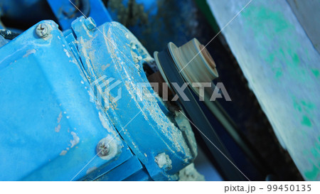 Close-up of the blue electric motor with belt that turns the concrete mixer. The work of the electric motor. Industry. 99450135