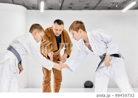 Greeting before fight session. Boys, children shaking hands, ready to train judo, jiu-jitsu exercises Greeting before fight session. Boys, children shaking hands, ready to train judo, jiu-jitsu exercises 99450732