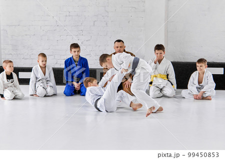 Boys, children in white kimono training judo, jiu-jitsu indoors with professional coach. Championship preparation 99450853