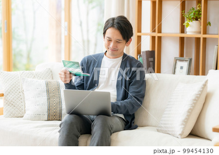 通帳を見て喜ぶ男性 通帳を見て喜ぶ男性 99454130