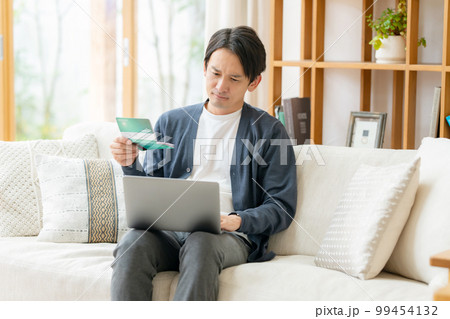 通帳を見て悩む男性 99454132