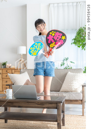 推し活 ライブ動画を見ながらうちわを振って推しを応援するz世代の女の子 推し活 ライブ動画を見ながらうちわを振って推しを応援するz世代の女の子 99456416