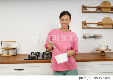 Young woman mixing with whisk kitchen bowl at kitchen table. Food making 99457369
