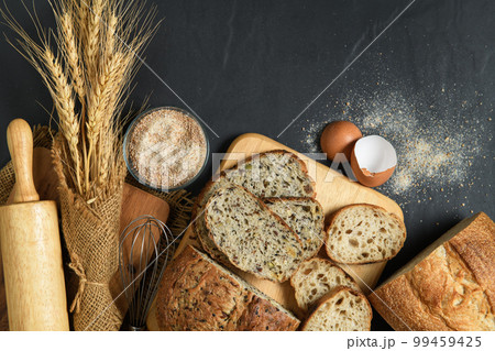 slide multi grain sourdough bread and sliced Baguette with Whole Wheat Flour on black stone background, 99459425