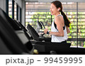 young happy asian woman athlete run on treadmill, running machine, in indoor gym fitness for health; 99459995