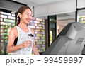 young happy asian woman athlete run on treadmill, running machine, in indoor gym fitness for health; 99459997