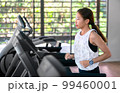 young happy asian woman athlete run on treadmill, running machine, in indoor gym fitness for health; 99460001
