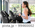 young happy asian woman athlete run on treadmill, running machine, in indoor gym fitness for health; 99460002