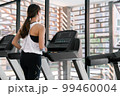 young happy asian woman athlete run on treadmill, running machine, in indoor gym fitness for health; 99460004