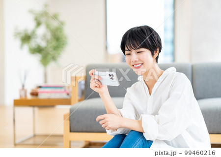 リビングでスマートフォンを操作する女性 リビングでスマートフォンを操作する女性 99460216