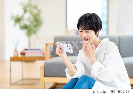 リビングでスマートフォンを操作する女性 リビングでスマートフォンを操作する女性 99460218