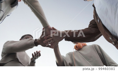 a group of faceless Friends stacking their hands together 99460381