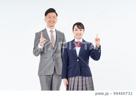 人差し指を立てるポーズをするスーツ姿の男性と女子高生 99460732