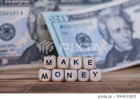 The words Make Money lined with letters on wooden cubes on the background of dollar bills. 99461905
