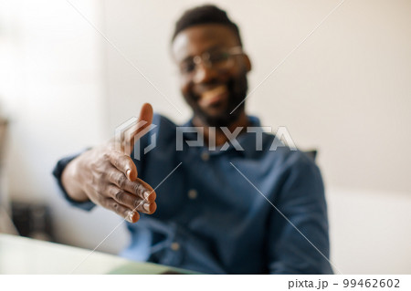 Black male entrepreneur extending hand for handshake at camera, offering partnership, greeting somebody, selective focus Black male entrepreneur extending hand for handshake at camera, offering partnership, greeting somebody, selective focus 99462602