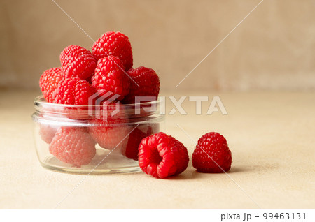 Fresh Raspberry in glass bowl, warm neutral background. Copy space 99463131