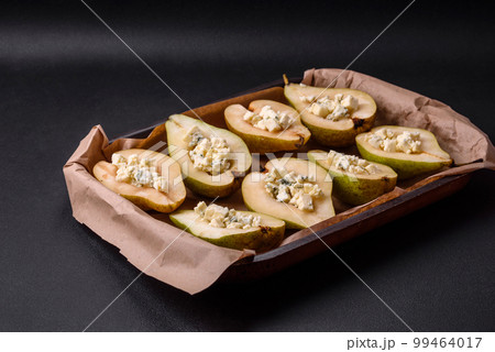 Delicious baked pear with dorblu cheese, walnut and honey on a textured concrete background 99464017