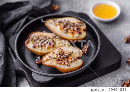 Delicious baked pear with dorblu cheese, walnut and honey on a textured concrete background 99464051