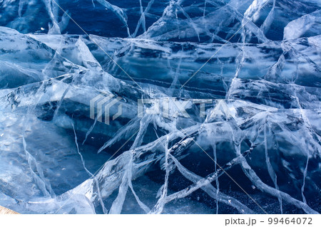 Many beautiful cracks in the clear blue ice. Layered thick ice. Horizontal. 99464072