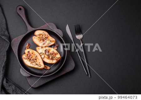 Delicious baked pear with dorblu cheese, walnut and honey on a textured concrete background Delicious baked pear with dorblu cheese, walnut and honey on a textured concrete background 99464073
