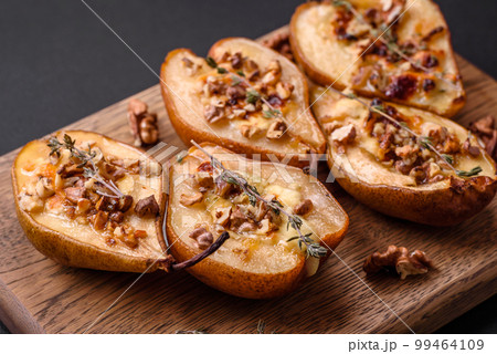 Delicious baked pear with dorblu cheese, walnut and honey on a textured concrete background Delicious baked pear with dorblu cheese, walnut and honey on a textured concrete background 99464109