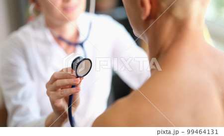 The doctor is touched by a stethoscope in a man, close-up The doctor is touched by a stethoscope in a man, close-up 99464131