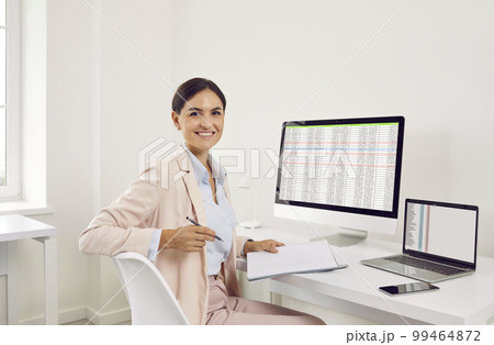 Happy smiling business woman accountant working on a laptop with tables at office. 99464872
