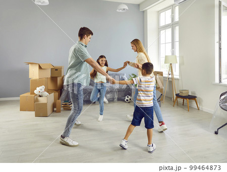 Happy joyful family dancing and having fun in their new spacious apartment on moving day 99464873
