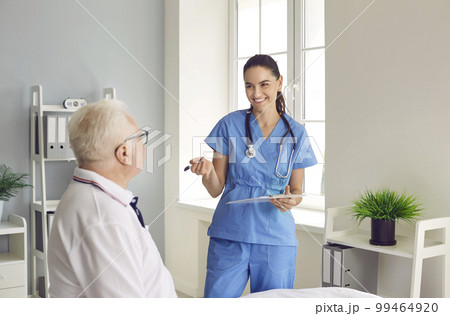 Smiling physician with clipboard interviewing senior patient during medical exam 99464920