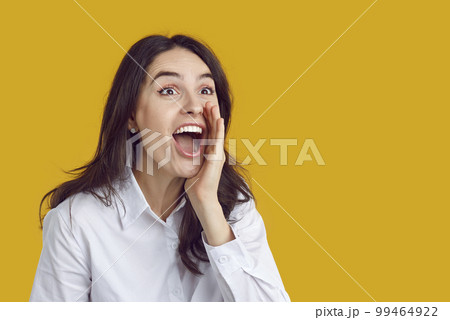 Joyful woman excitedly shouts something interesting to crowd, holding her hand to her mouth. Joyful woman excitedly shouts something interesting to crowd, holding her hand to her mouth. 99464922