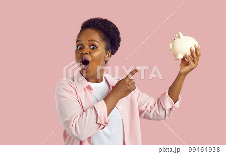 Portrait of astonished amazed african american woman holding piggy bank in hands. Portrait of astonished amazed african american woman holding piggy bank in hands. 99464938
