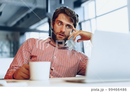 Puzzled thoughtful businessman sitting at his working table in an office Puzzled thoughtful businessman sitting at his working table in an office 99466486
