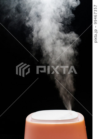 Steam from pink humidifier on a black background.  99467357