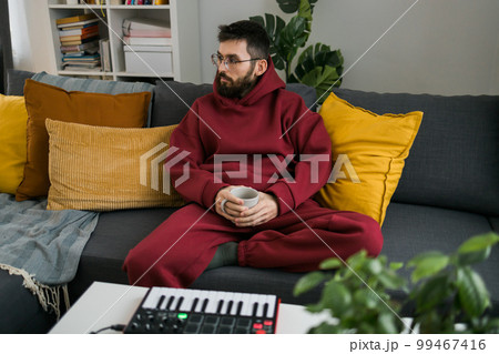 Man recording electronic music track with portable midi keyboard on laptop computer in home studio. Producing and mixing music beat making and arranging audio content with professional audio devices 99467416